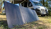 Solarpanel, Campingbus, Photovoltaik, Camping, Stromversorgung, Outdoor, Vanlife, Solarmodul, Energieversorgung, Wald Tragbares Solarpanel auf dem Boden vor einem Campingbus im Wald.